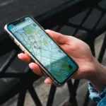 Tangan memegang smartphone yang menampilkan aplikasi peta untuk pelacakan lokasi di luar ruangan